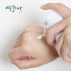 Hand applying a white cream to another hand on a light background