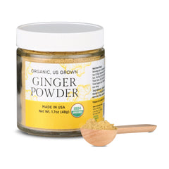 Jar of NUF organic ginger powder with a wooden scoop on a white background