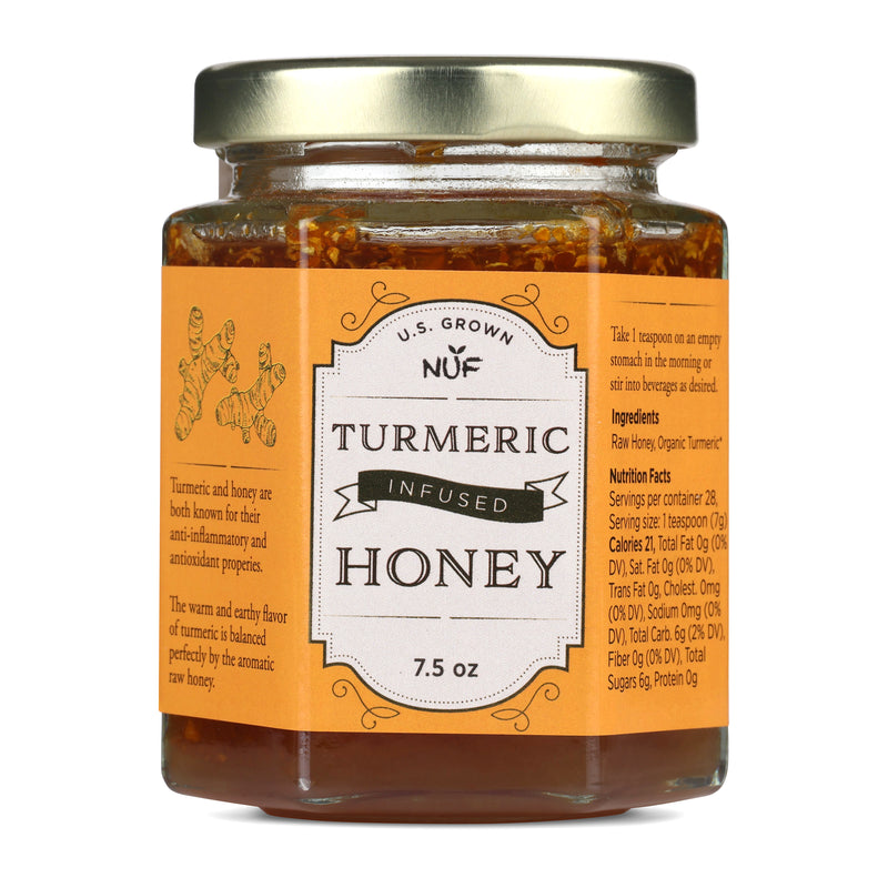 Jar of turmeric infused honey with a gold lid on a white background