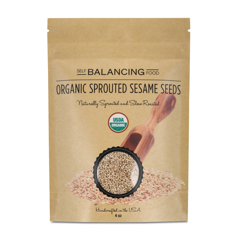 Paper package of organic sprouted sesame seeds with a wooden scoop on a white background.
