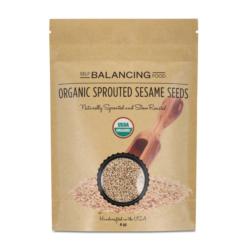 Paper package of organic sprouted sesame seeds with a wooden scoop on a white background.