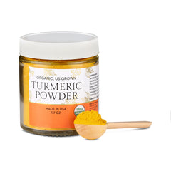 Jar of turmeric powder with a wooden spoon on a white background